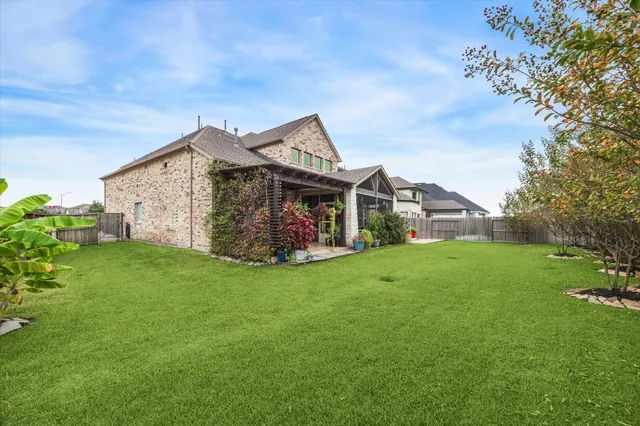 a view of a house with a big yard potted plants and large tree