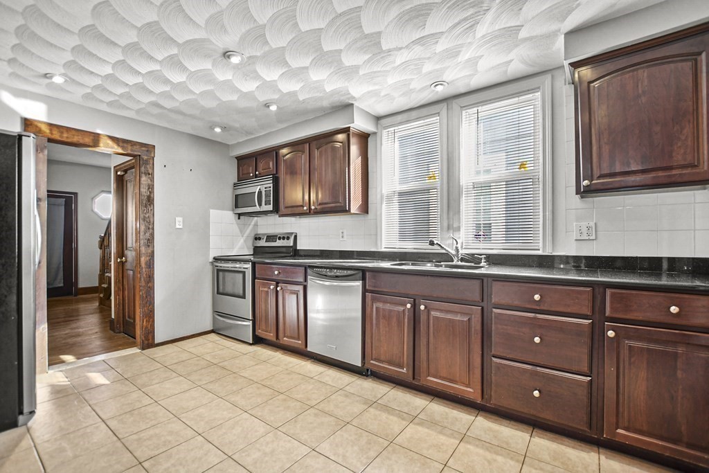 242 Eastern Avenue Lynn, MA 01902 - Photo 3 of 23 a kitchen with stainless steel appliances granite countertop a stove a sink and a refrigerator
