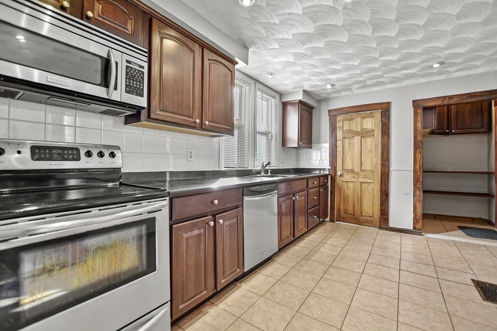 242 Eastern Avenue Lynn, MA 01902 - Photo 5 of 23 a kitchen with stainless steel appliances granite countertop a stove a sink and a microwave