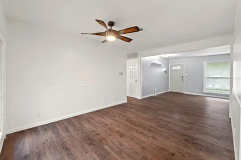 a view of empty room with wooden floor and fan