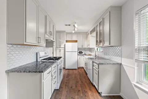 a kitchen with granite countertop a sink stove and refrigerator