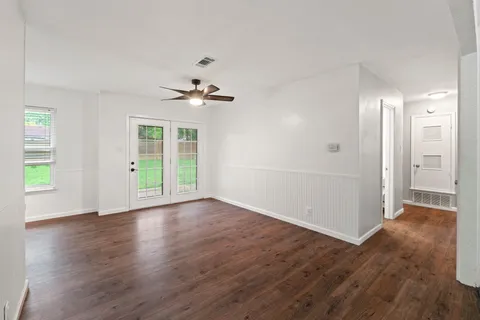 a view of an empty room with window and wooden floor
