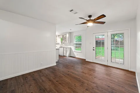 a view of an empty room with a window and wooden floor