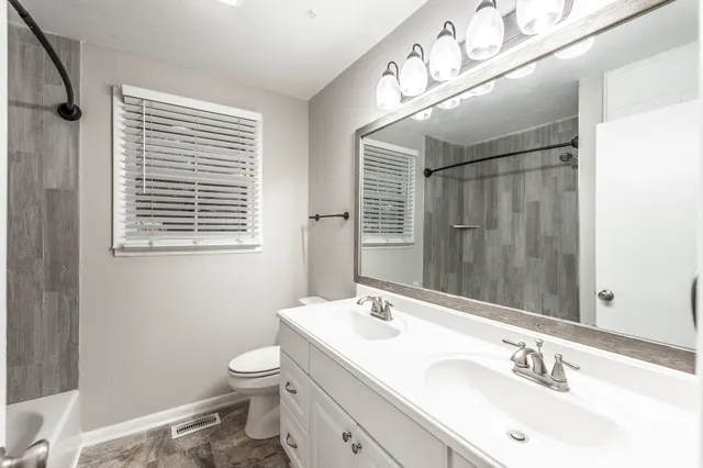 a bathroom with a granite countertop sink toilet a mirror and shower