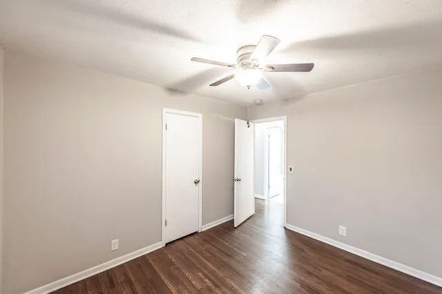 an empty room with wooden floor and ceiling fan