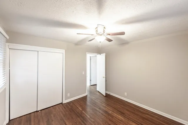 an empty room with wooden floor ceiling fan and windows