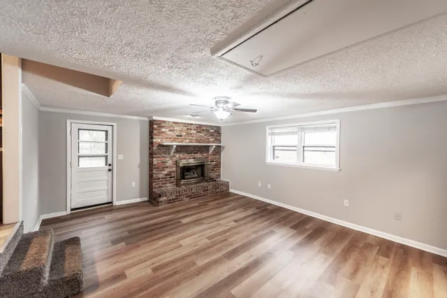 an empty room with windows fireplace and wooden floor