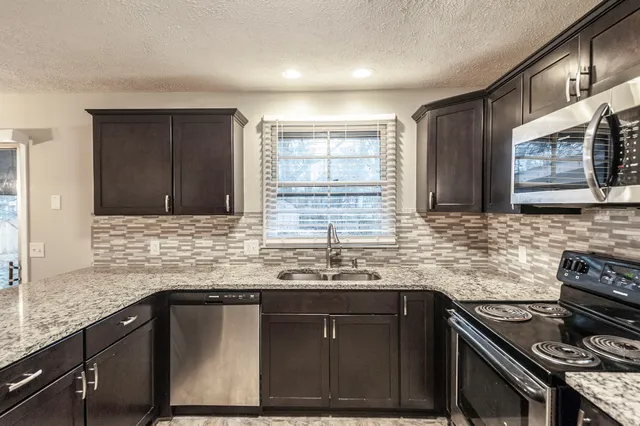 a kitchen with stainless steel appliances granite countertop a sink stove and cabinets
