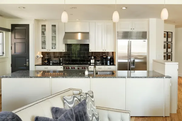 a kitchen with stainless steel appliances kitchen island granite countertop a refrigerator a stove and a sink with wooden floor