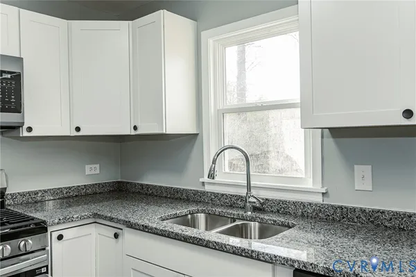 a kitchen with granite countertop a sink a window and cabinets