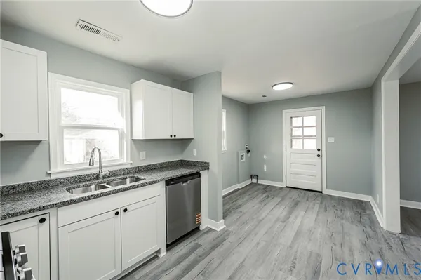 a kitchen with granite countertop wooden floors white cabinets and sink