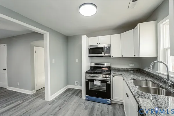 a kitchen with granite countertop a stove a sink and a microwave