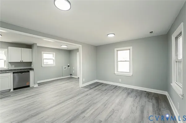 a view of an empty room with window and wooden floor
