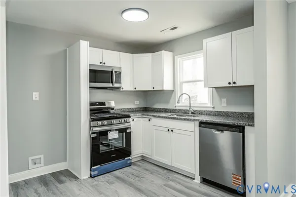 a kitchen with stainless steel appliances granite countertop a stove a sink and a microwave