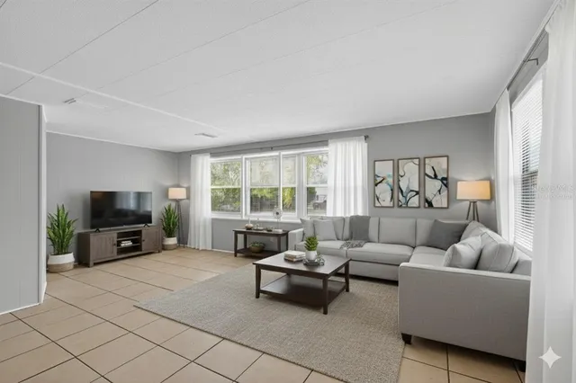 a living room with furniture a flat screen tv and a large window