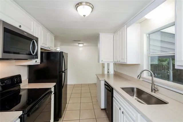 a kitchen with stainless steel appliances a sink a stove a microwave a sink a refrigerator and cabinets