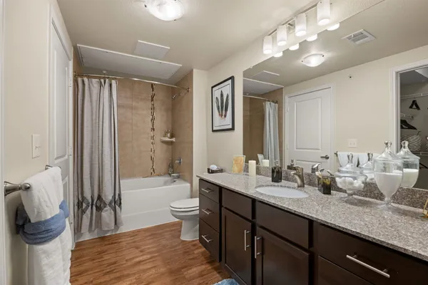 a bathroom with double vanity sinks a toilet a mirror and shower