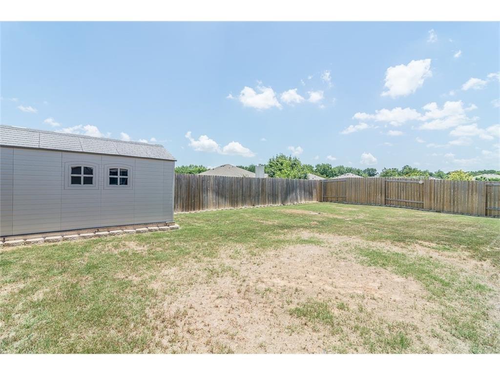 1009 Hawthorne Road Anna, TX 75409 - Photo 22 of 22 Expansive fenced backyard featuring a storage shed with arched window details and a full privacy fence