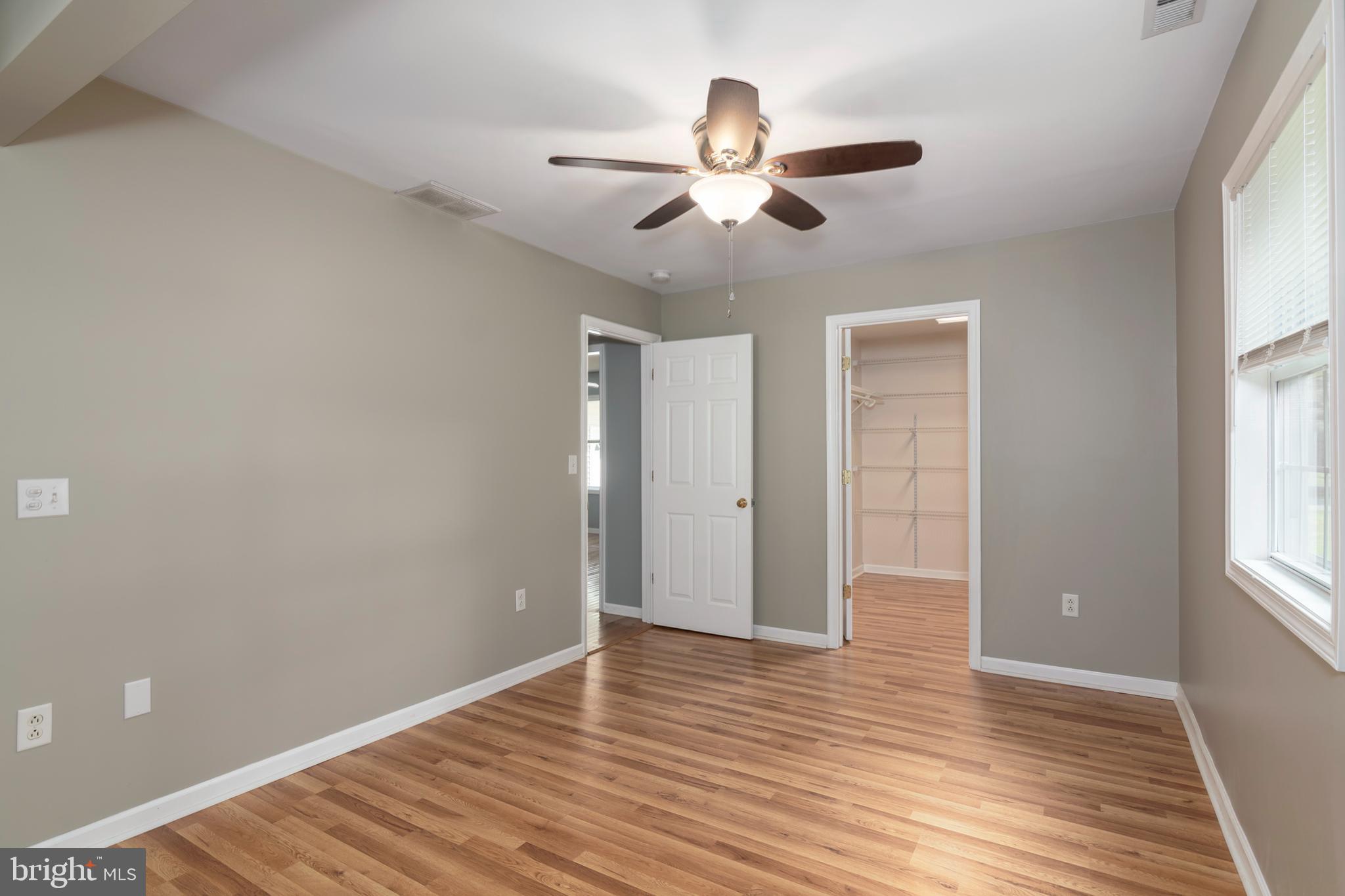6824 Hopkins Neck Road Easton, MD 21601 - Photo 20 of 45 an empty room with wooden floor chandelier fan and windows
