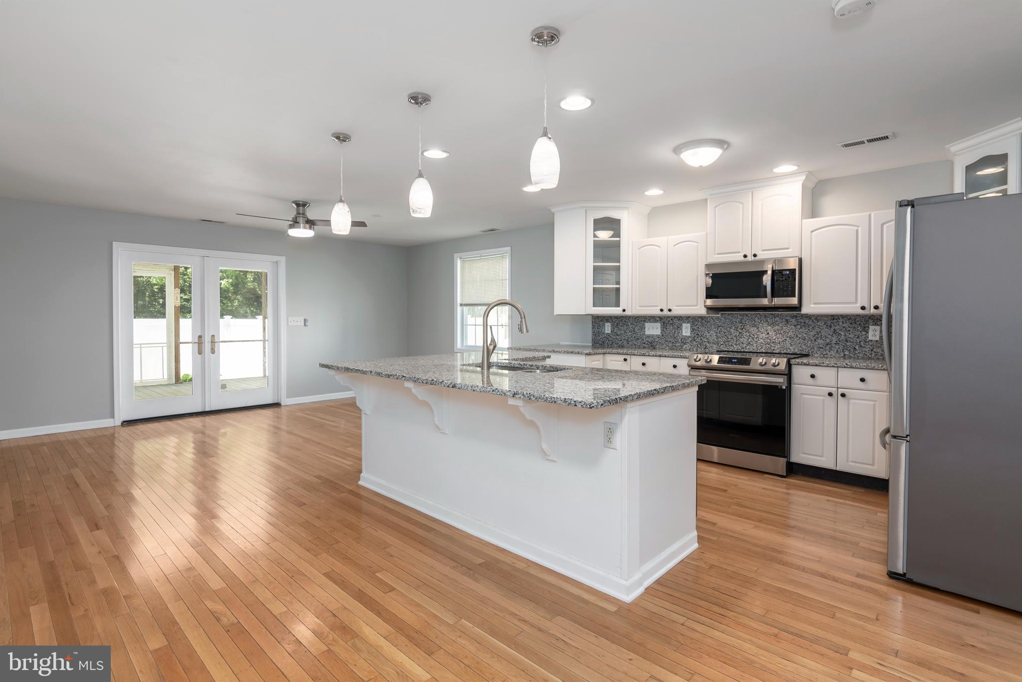 6824 Hopkins Neck Road Easton, MD 21601 - Photo 5 of 45 a kitchen with stainless steel appliances granite countertop a stove top oven a sink dishwasher a refrigerator and a dining table with wooden floor