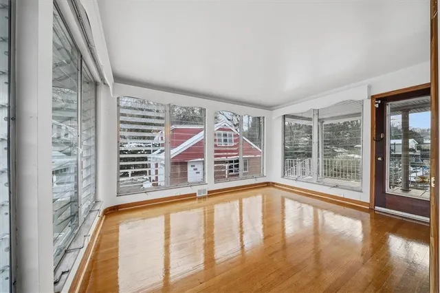 a view of an empty room with wooden floor and windows