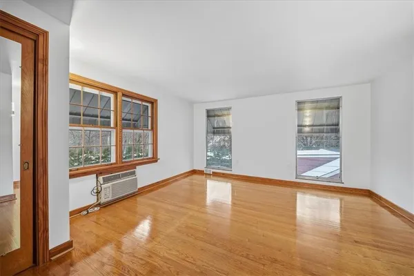 a view of an empty room with a window and wooden floor