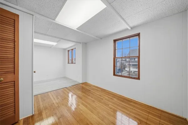 a view of empty room with wooden floor and fan