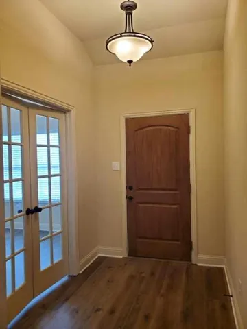 an empty room with wooden floor closet and windows
