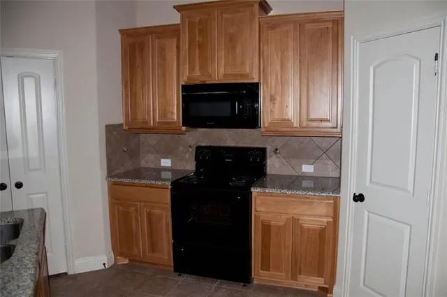 a kitchen with granite countertop white cabinets and stainless steel appliances