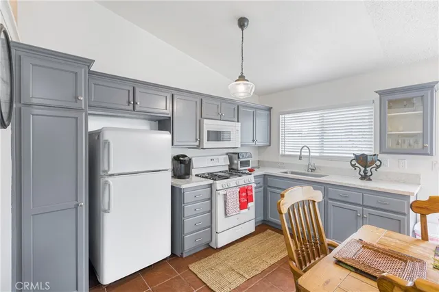 a kitchen with a refrigerator a sink dishwasher a dining table and chairs with wooden floor