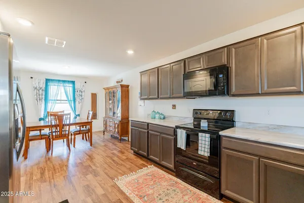 a kitchen with stainless steel appliances granite countertop a stove top oven a sink dishwasher a dining table and chairs with wooden floor