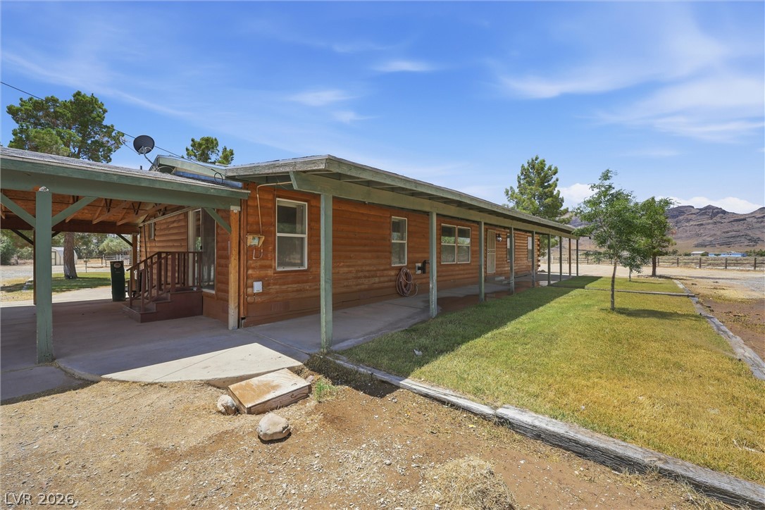 1531 West Harris Farm Road Pahrump, NV 89060 - Photo 8 of 37 A rustic wood-sided home with a covered porch awaits amidst a tranquil, mountainous backdrop.