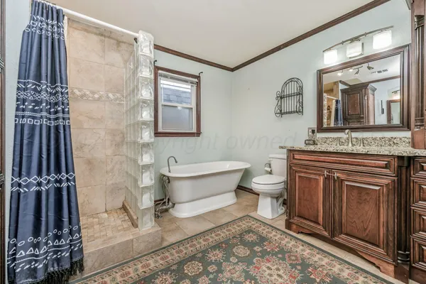 a spacious bathroom with a granite countertop sink toilet a mirror and shower