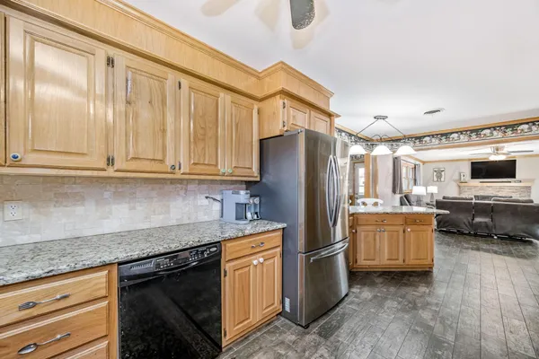 a kitchen with stainless steel appliances granite countertop a refrigerator a stove and a sink with wooden cabinets