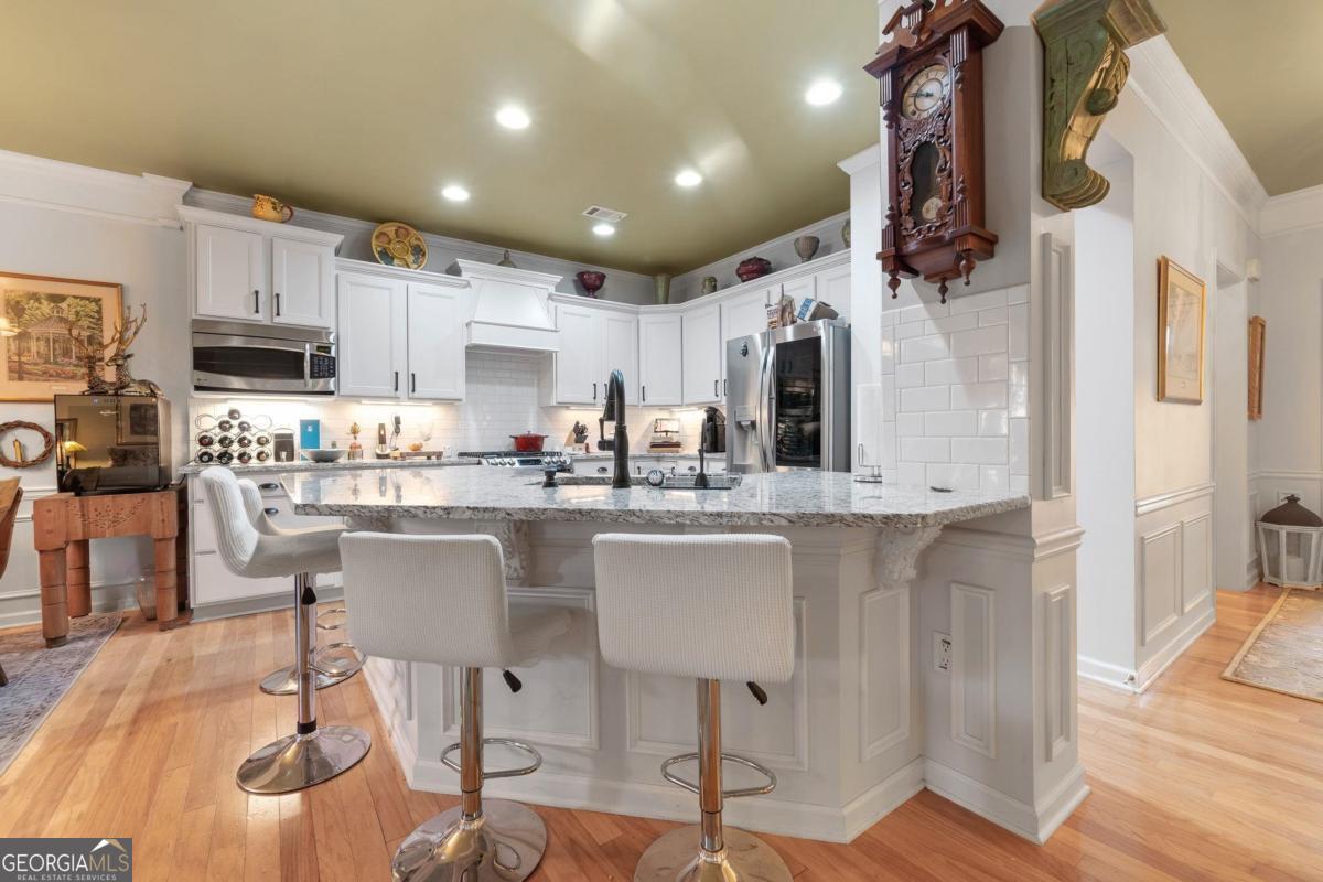 1151 Spring Station Road Greensboro, GA 30642 - Photo 13 of 60 a kitchen with stainless steel appliances granite countertop a refrigerator a stove top oven a sink dishwasher and white cabinets with wooden floor