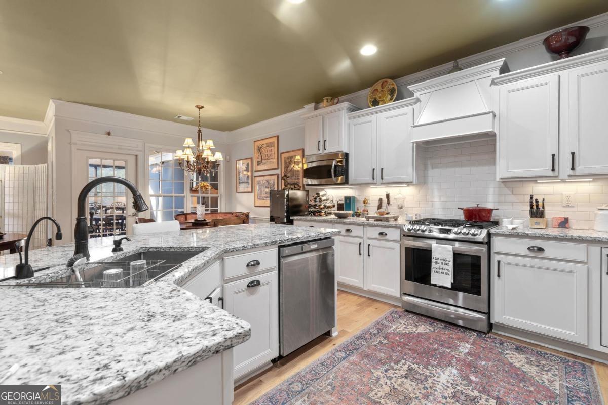 1151 Spring Station Road Greensboro, GA 30642 - Photo 21 of 60 a kitchen with kitchen island granite countertop a sink stainless steel appliances and white cabinets