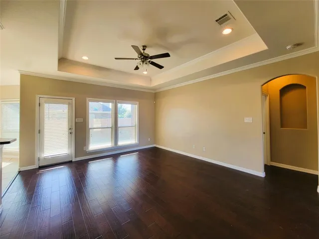 a view of empty room with wooden floor and fan