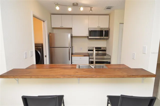 a kitchen with stainless steel appliances granite countertop a refrigerator and a stove top oven