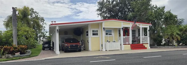 a view of a house with a small yard and a large tree