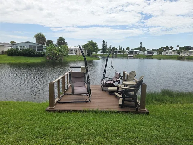 a view of a lake with table and chairs next to a yard