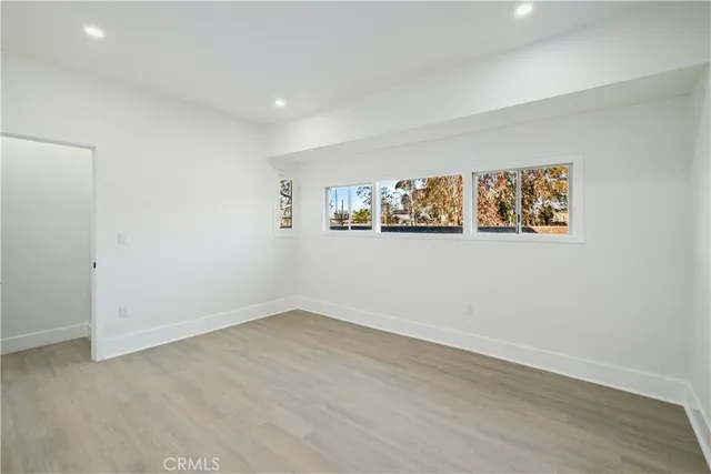 a view of an empty room with wooden floor and window