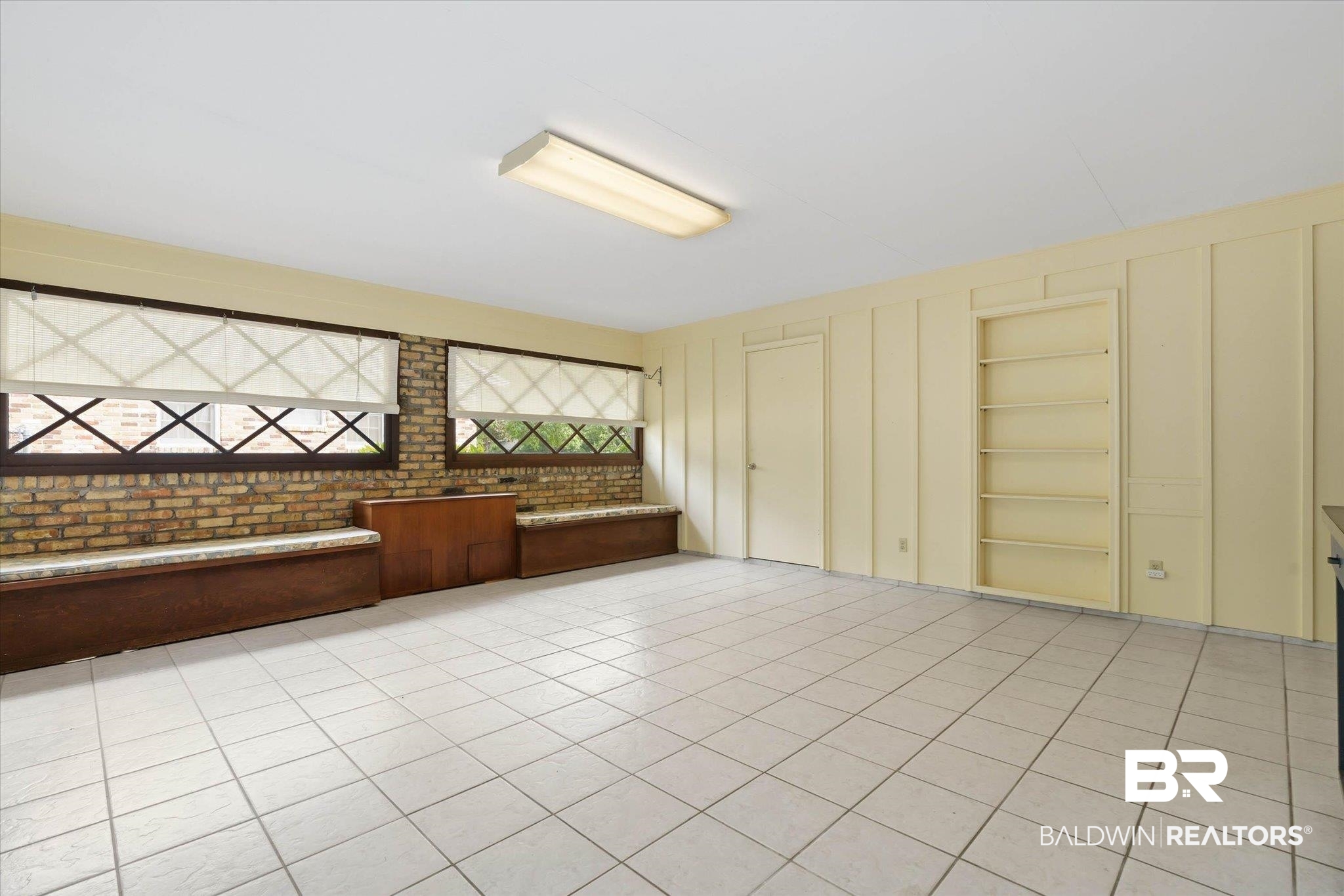 1182 Ginger Drive Mobile, AL 36693 - Photo 29 of 37 Spacious room featuring light-toned tile flooring, two windows with decorative grilles and roller shades, built-in wooden benches with cushioned tops, a built-in shelving unit, and a flush-mount overhead light fixture