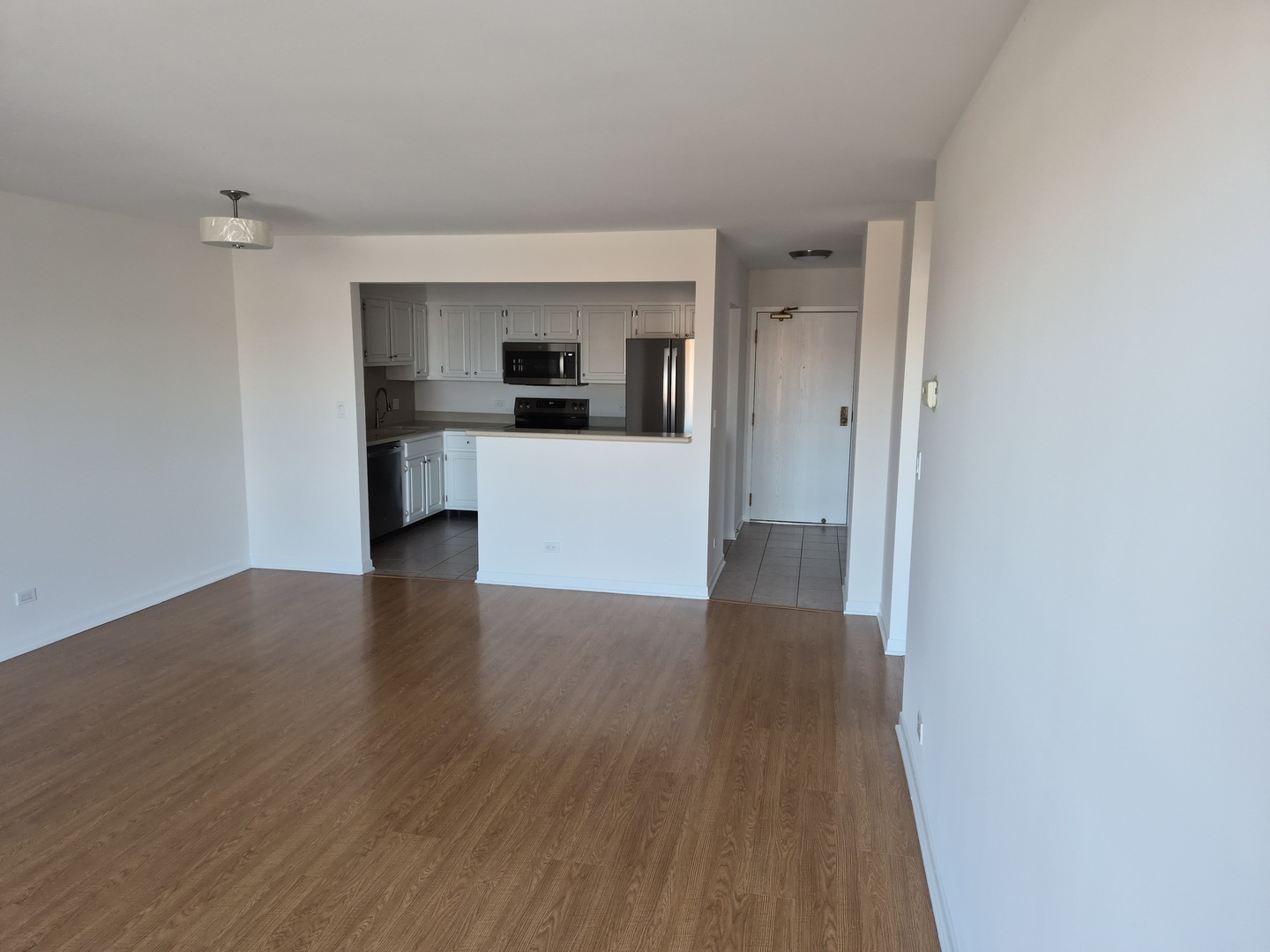 711 South River Road, Unit 704 Des Plaines, IL 60016 - Photo 4 of 15 a view of kitchen and microwave with wooden floor