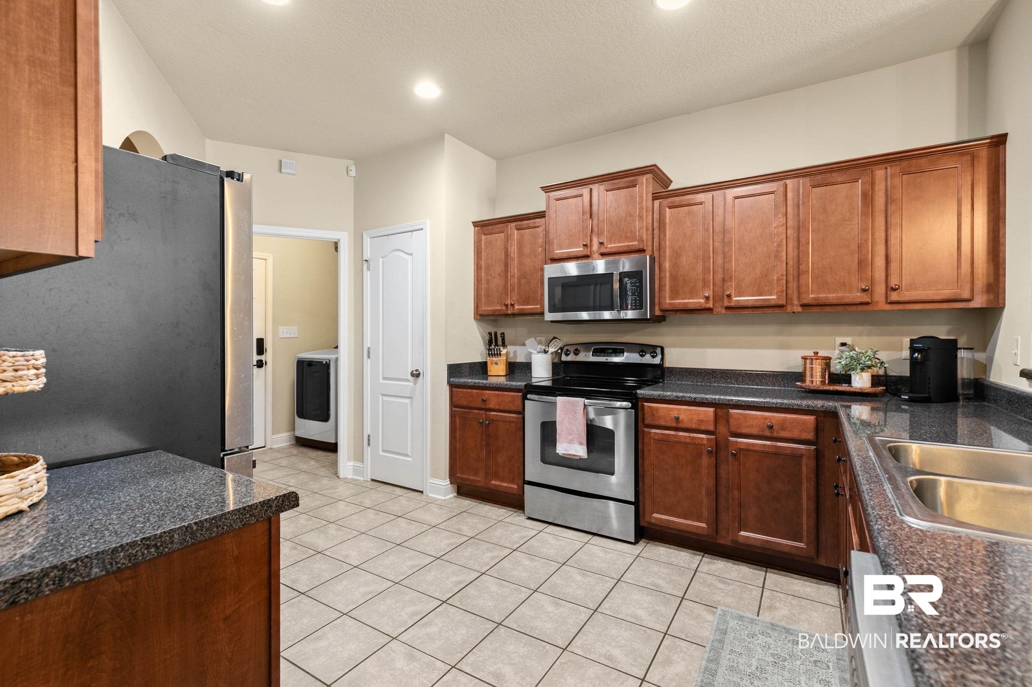 2216 Livingstone Court Mobile, AL 36695 - Photo 15 of 62 Kitchen featuring ample wood cabinetry, dark speckled countertops, and stainless steel appliances