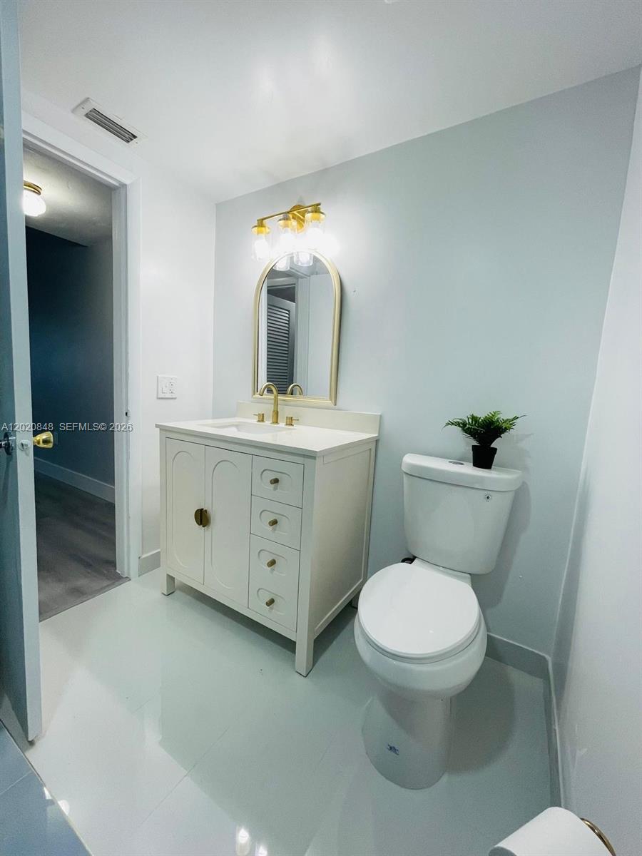 9175 Southwest 77th Avenue, Unit 306 Miami, FL 33156 - Photo 13 of 16 a bathroom with a toilet sink and mirror