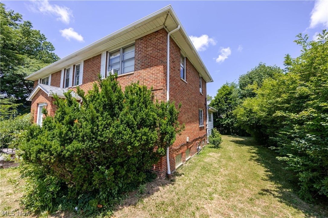 3825 Mayfield Road Cleveland Heights, OH 44121 - Photo 2 of 27 Brick exterior featuring white window trim, a covered entry, established front landscaping, white gutters, and a grassy side yard