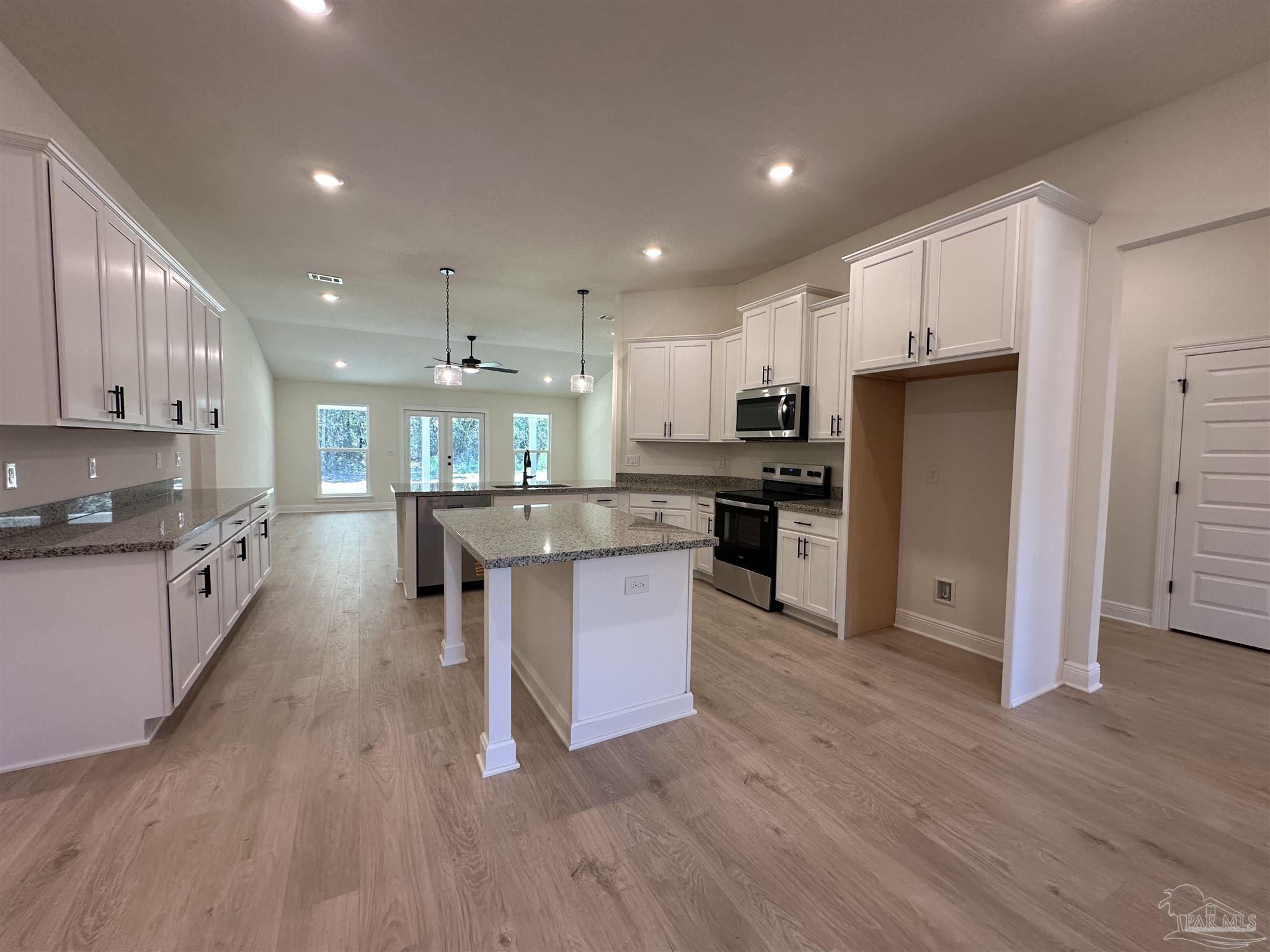 5223 Wahoo Road Milton, FL 32583 - Photo 11 of 26 a kitchen with stainless steel appliances kitchen island granite countertop a refrigerator a stove a sink a microwave and island with wooden floor