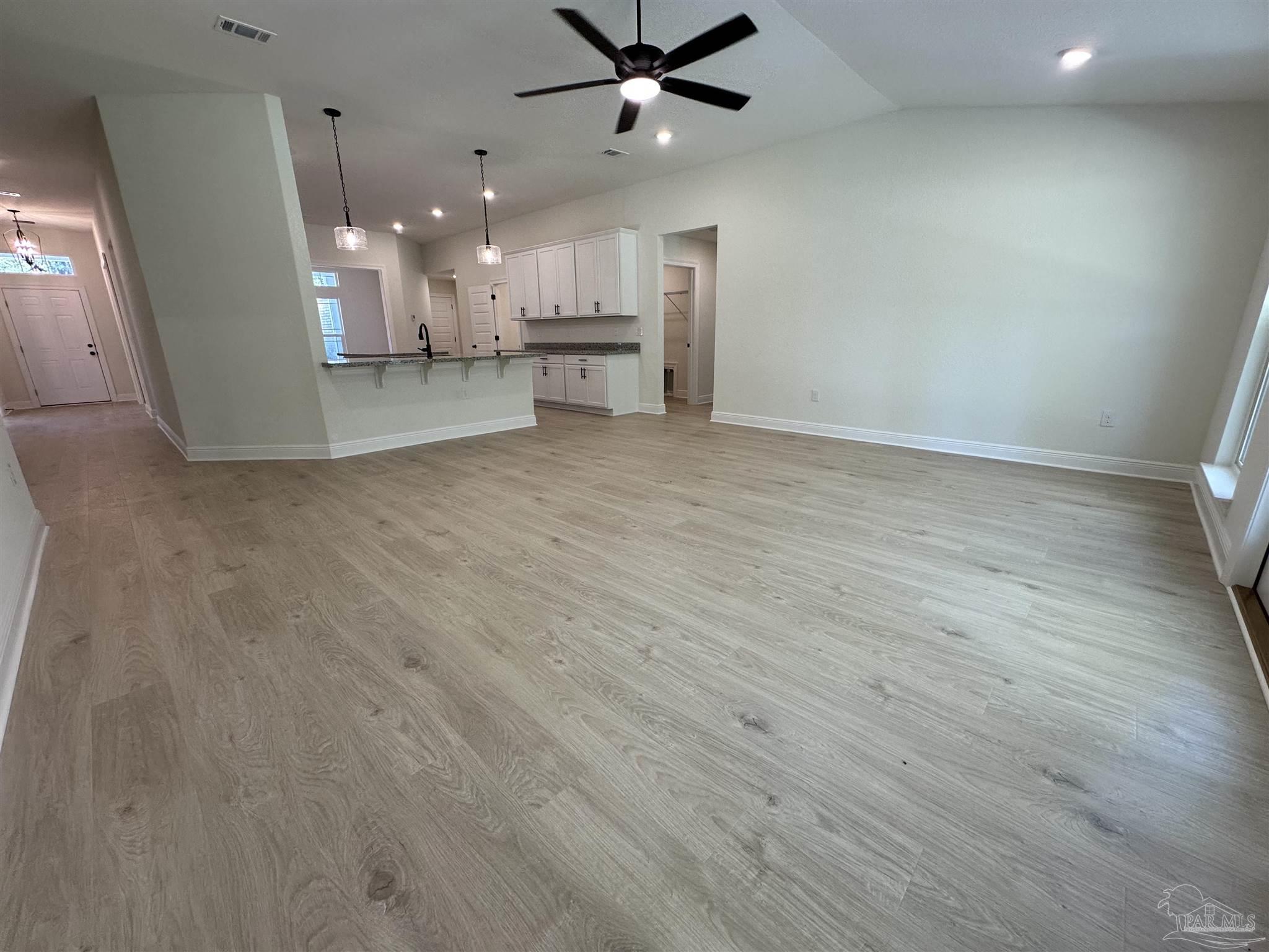 5223 Wahoo Road Milton, FL 32583 - Photo 17 of 26 an empty room with wooden floor kitchen view and a chandelier
