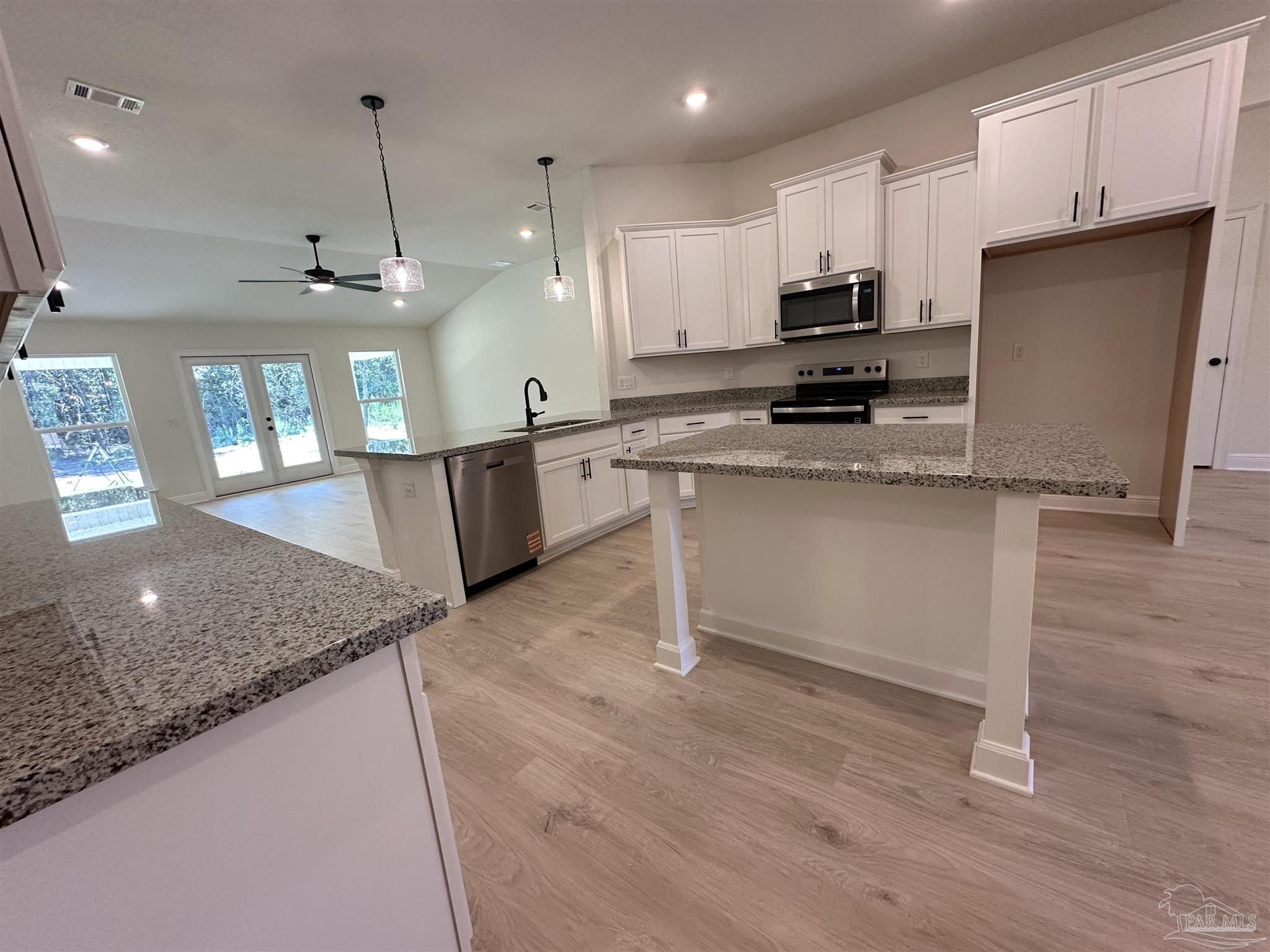 5223 Wahoo Road Milton, FL 32583 - Photo 5 of 26 a kitchen with stainless steel appliances granite countertop a sink a stove a refrigerator and island with wooden floor