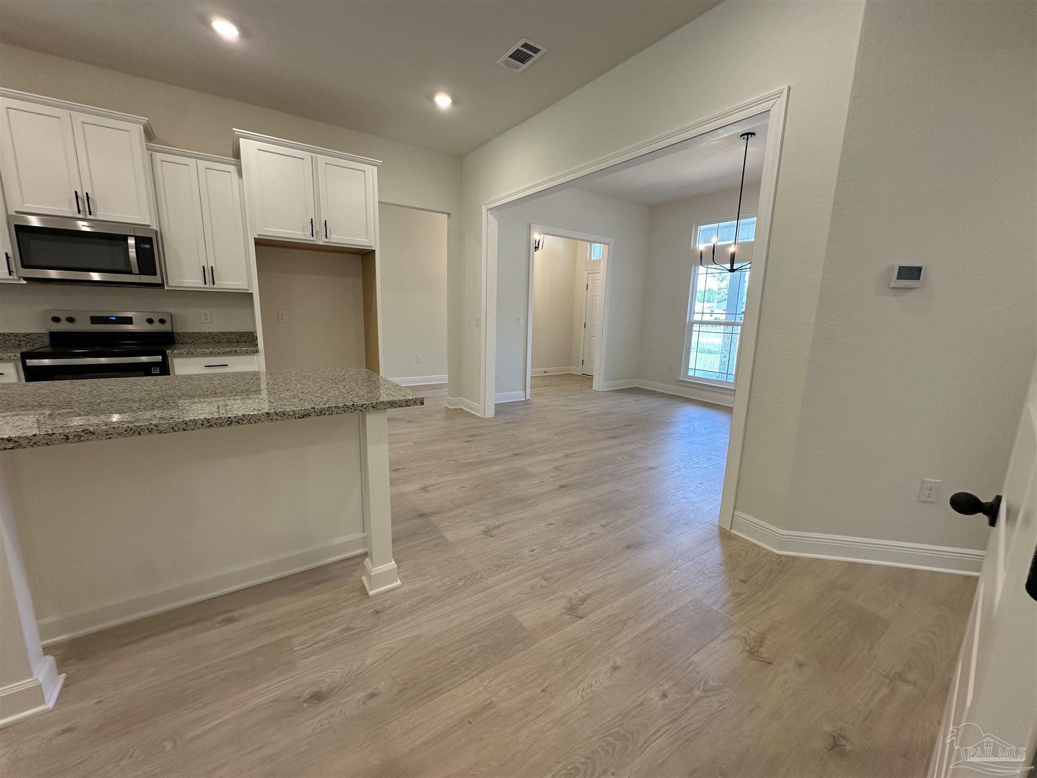5223 Wahoo Road Milton, FL 32583 - Photo 7 of 26 a kitchen with granite countertop a refrigerator and a stove top oven